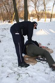 na zdjęciu jest policjant, który interweniuje wobec osoby leżącej na śniegu