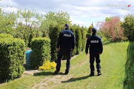 na zdjęciu widnieje policjant umundurowany  patrolujący teren ogródków działkowych