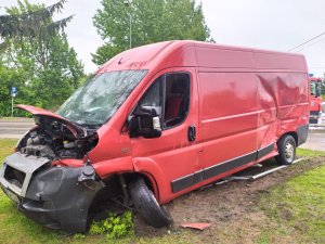 na obrazku znajduje się samochód dostawczy koloru czerwonego z uszkodzoną maska oraz bokiem pojazdu