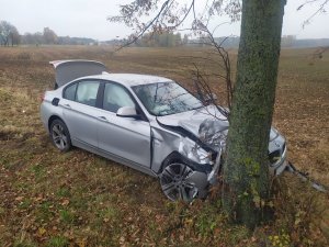 na zdjęciu jest szare bmw, które w wyniku niewłaściwego manewru kierowcy uderzyło w drzewo. auto ma rozbitą przednią maskę. w pojeździe nie ma osób.