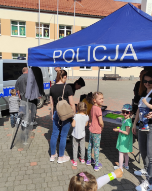 na zdjęciu znajduje się stoisko policyjne z radiowozem policyjnym obok którego stoją dzieci i dorośli
