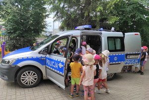 na zdjęciu znajduje się policyjny radiowóz, przy którym stoją dzieci