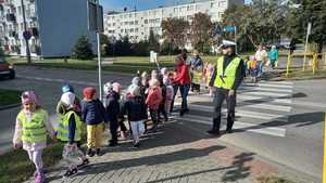 na zdjęciu znajduje się policjant na drodze, przy którym stoi grupa dzieci