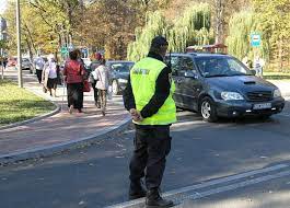 na zdjęciu widnieje policjant umundurowany, który nadzoruje ruch drogowy w okolicy cmentarza