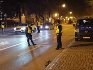 na zdjęciu są policjanci umundurowani, którzy na głównej ulicy w Giżycku zatrzymują do kontroli drogowej kierujących, sprawdzają ich stan trzeźwości