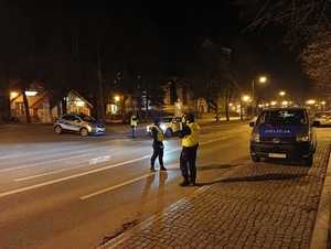 na zdjęciu są policjanci umundurowani, którzy na głównej ulicy w Giżycku zatrzymują do kontroli drogowej kierujących, sprawdzają ich stan trzeźwości